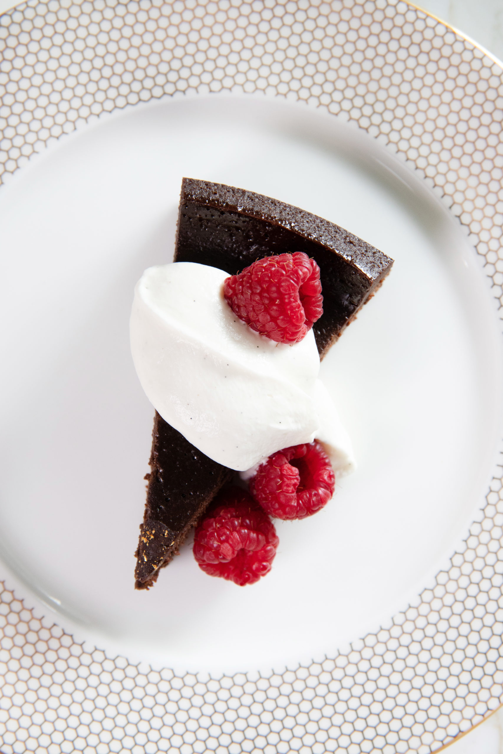 image of flourless chocolate cake plated with raspberries