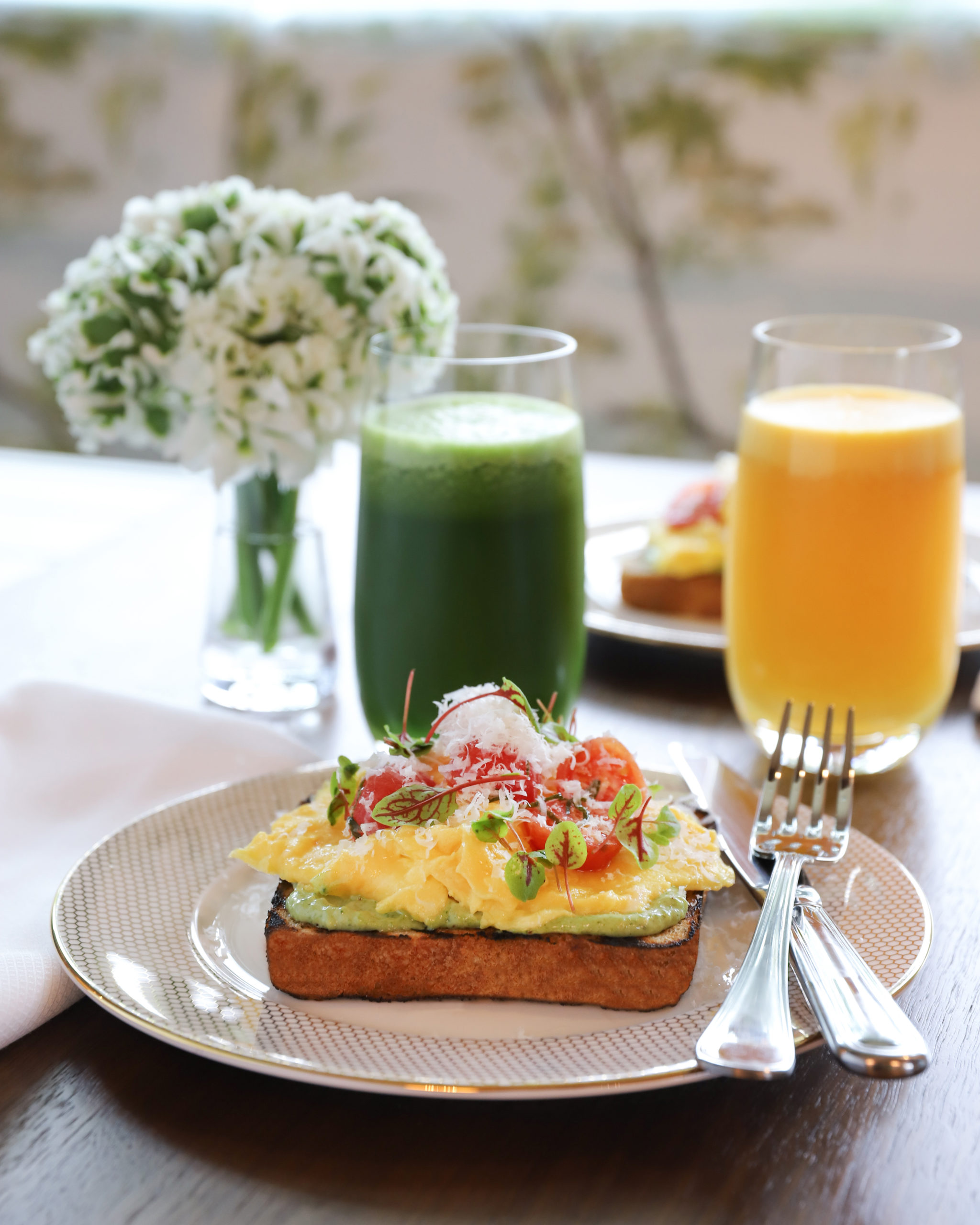 image of avocado toast with fresh pressed orange and green juices on table
